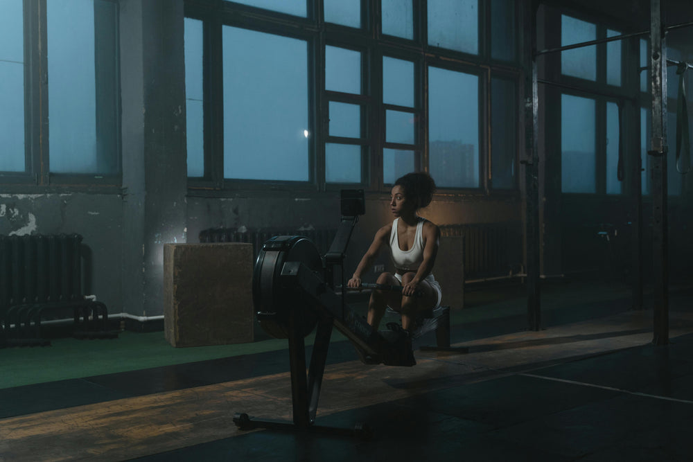 Woman training on rowing machine in moody industrial gym setting